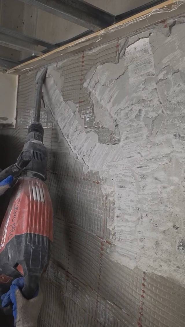 Breaker hammer chipping tile bed off a wall