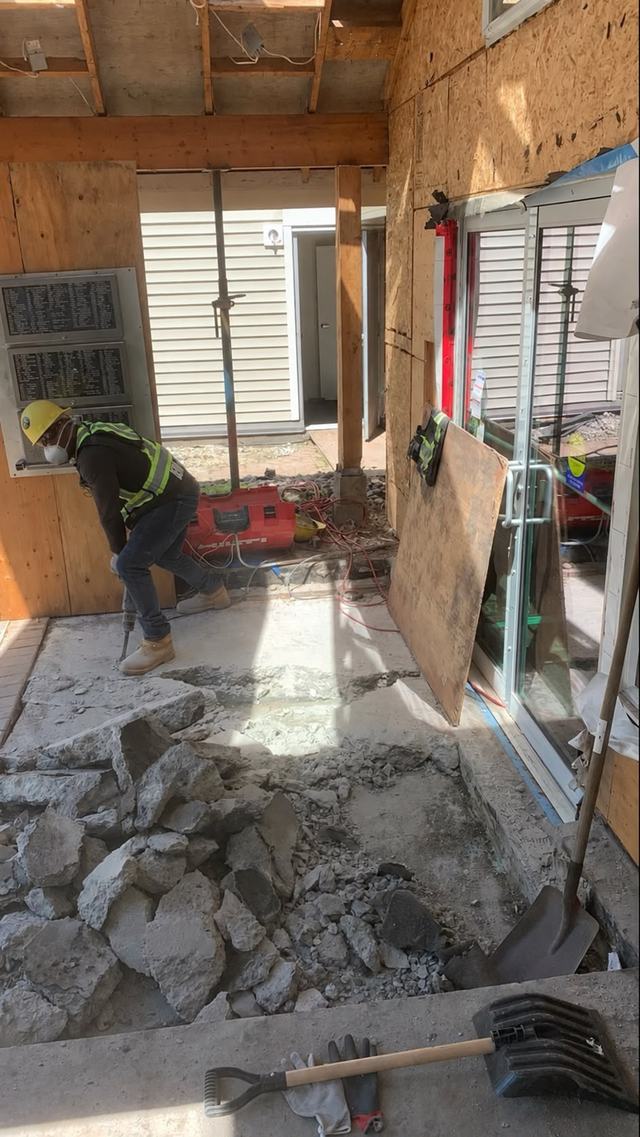 Crew member breaking up a concrete slab with a jackhammer
