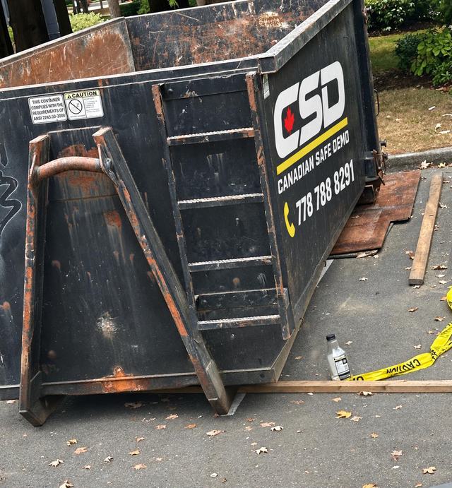 Canadian Safe Demo debris bin on site with the company logo and phone number