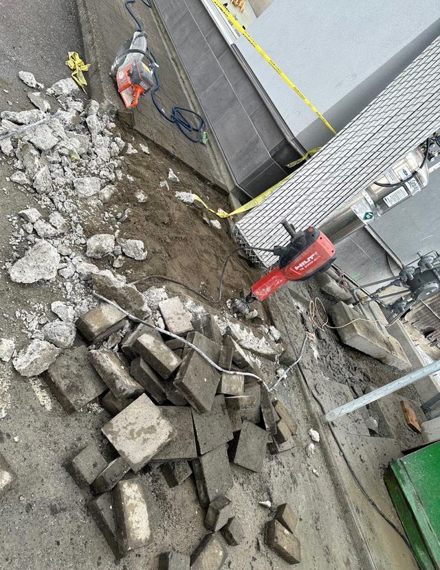 Broken concrete and pavers with breaker hammers on an exterior demolition site